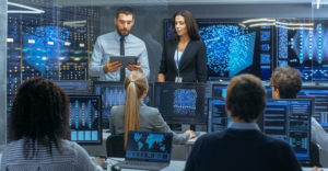 Technology leaders and IT staff review data and AI systems in an enterprise operations center.