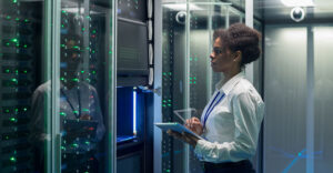 IT professional reviewing cloud data center systems inside a server aisle.