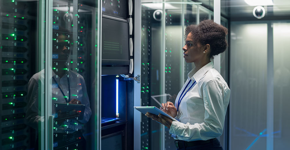 IT professional reviewing cloud data center systems inside a server aisle.