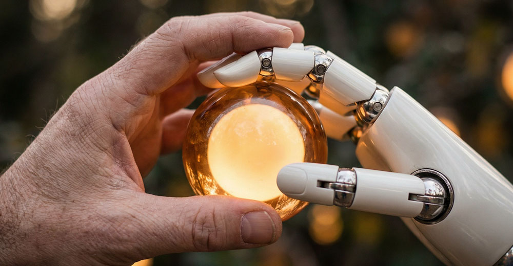 Human and robotic hands holding a glowing sphere symbolizing collaboration between artificial intelligence and human decision-making