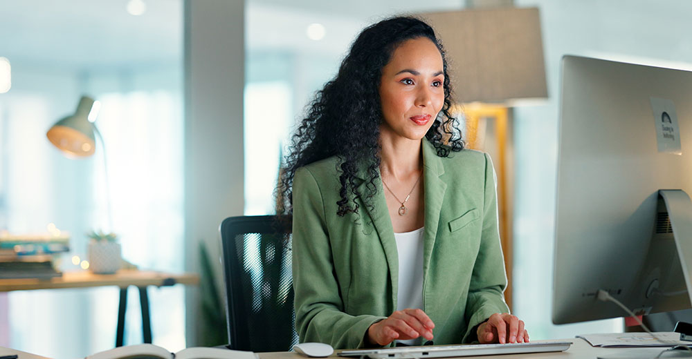 A communications professional works at a desktop computer as companies adapt PR and marketing strategies for AI-driven search and online visibility.